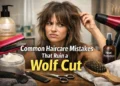 A woman with a messy wolf cut hairstyle surrounded by hair products and styling tools, showing common haircare mistakes that ruin layered wolf cut hair.